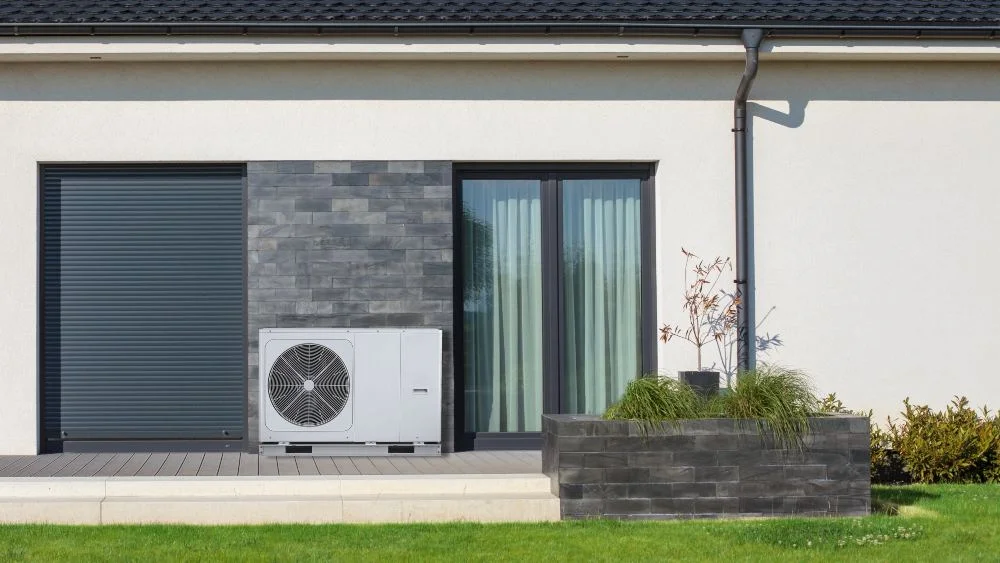 Pompe à chaleur air-air moderne installée à l’extérieur, avec une grille frontale et un boîtier gris foncé.